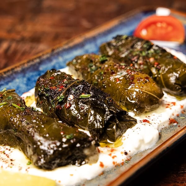 Dolmades, grape leaves stuffed with rice and herbs, served on yogurt with spices and lemon.